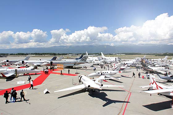 Eine große Anzahl an Business-Jets stehen auf einem Flughafen.